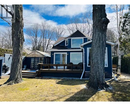 A blue house with a deck and trees in the background.