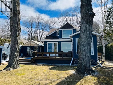 A blue house with a deck and trees in the background.