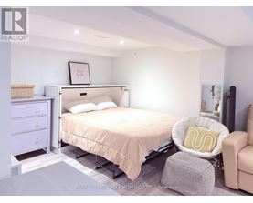 A bedroom with a bed, chair, and nightstand.
