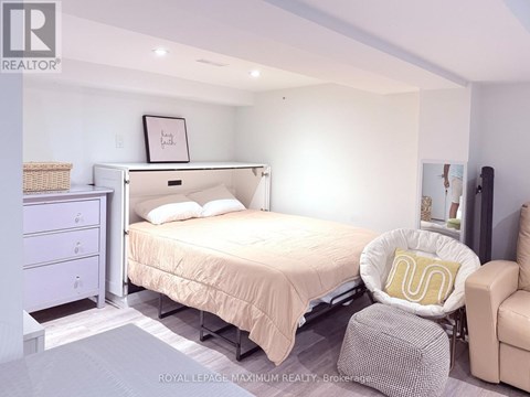 A bedroom with a bed, chair, and nightstand.