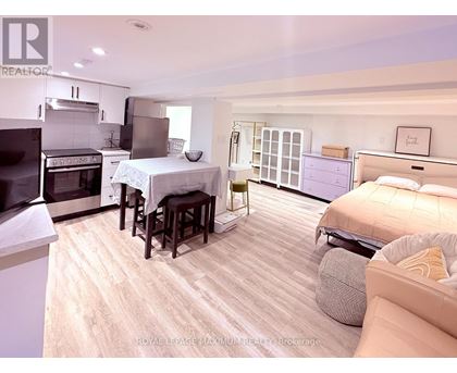 A well-lit, spacious bedroom with a large bed and a kitchen area with a stove and oven.