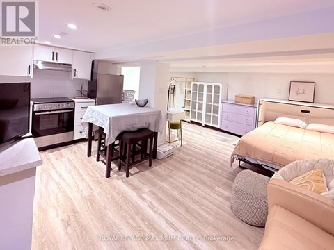 A well-lit, spacious bedroom with a large bed and a kitchen area with a stove and oven.