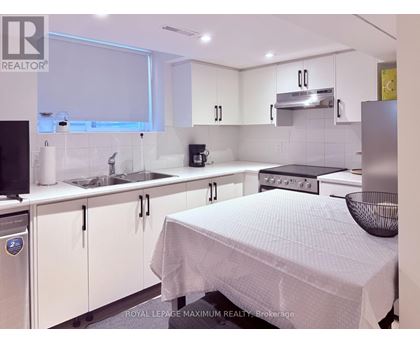 A white kitchen with a bed in the middle.