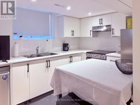 A white kitchen with a bed in the middle.