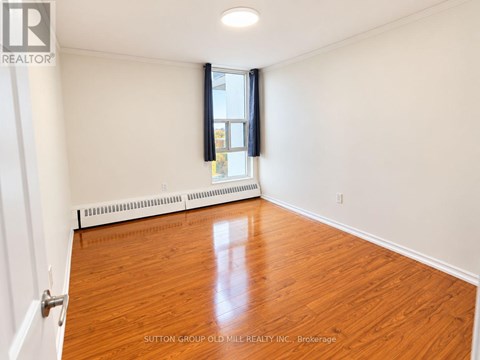 A room with wooden flooring and a window with blinds.