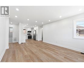 A spacious room with wooden flooring and white walls.