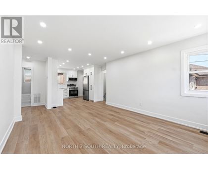A spacious room with wooden flooring and white walls.