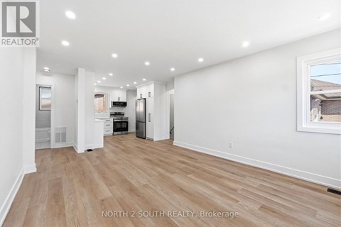 A spacious room with wooden flooring and white walls.