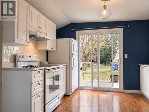 A kitchen with white appliances and wooden floors.