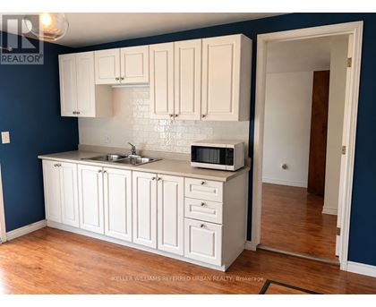 A kitchen with white cabinets and a blue wall.