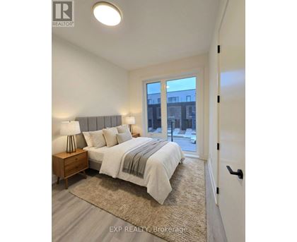 A bedroom with a bed, nightstand, and a window overlooking a cityscape.