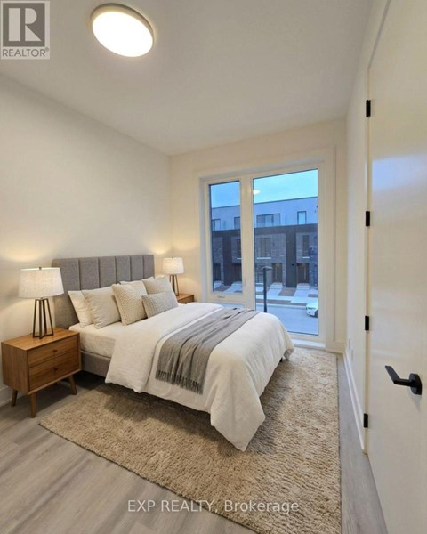 A bedroom with a bed, nightstand, and a window overlooking a cityscape.