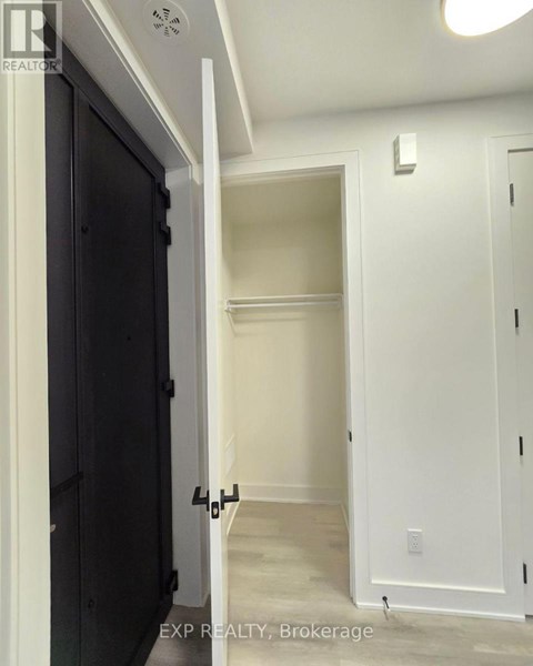 A hallway with a black door on the left and a white door on the right.