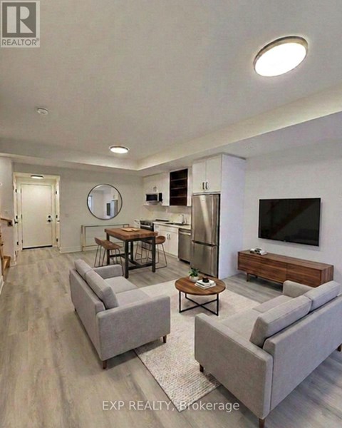 A modern living room with a grey sofa, a wooden coffee table, and a flat-screen TV mounted on the wall.