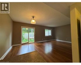 A room with wooden floors and a sliding glass door leading to a backyard.
