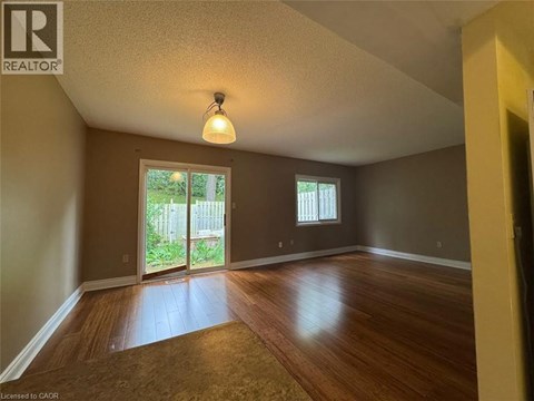 A room with wooden floors and a sliding glass door leading to a backyard.
