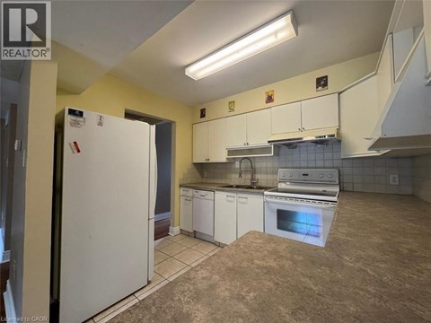 A kitchen with a white fridge and white cabinets.