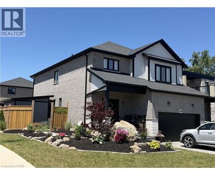 A modern house with a grey and white exterior and a landscaped front yard.