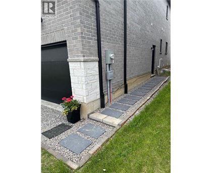 A grey brick building with a black door and a grey stone walkway.