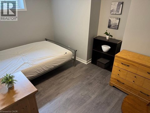 A bedroom with a bed, nightstand, and a wooden dresser.