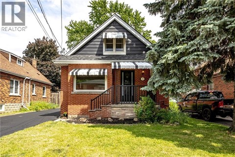 A small brick house with a black awning and a black truck parked in front.