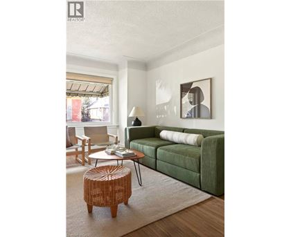A living room with a green couch, a wooden stool, and a painting on the wall.