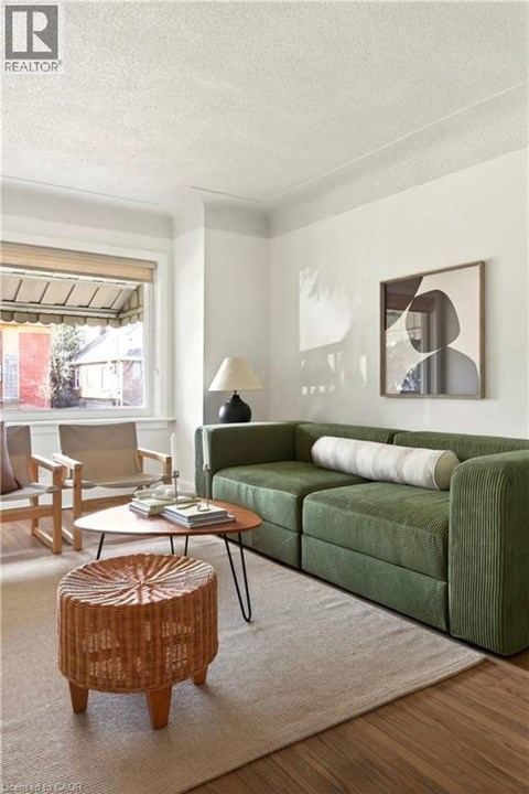 A living room with a green couch, a wooden stool, and a painting on the wall.