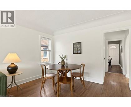 A dining room with a table set for two and a cat in the hallway.