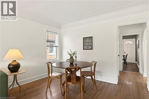 A dining room with a table set for two and a cat in the hallway.