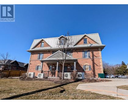 A large brick house with a porch and a tree in front.