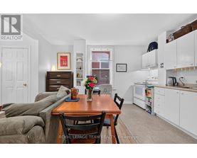A dining room with a table set for two and a couch.