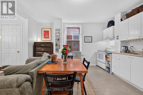 A dining room with a table set for two and a couch.