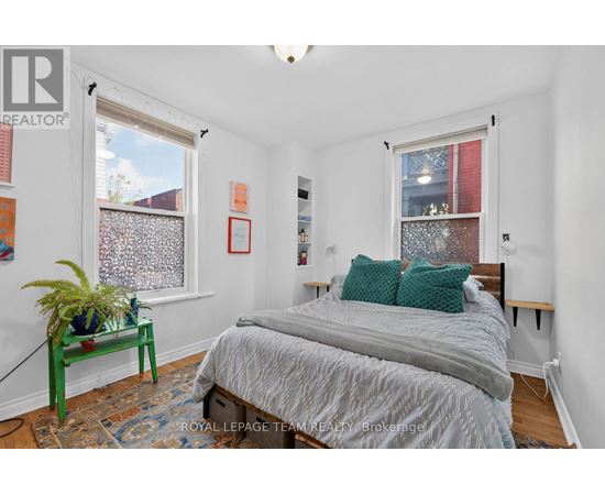A bedroom with a bed, nightstand, and window.