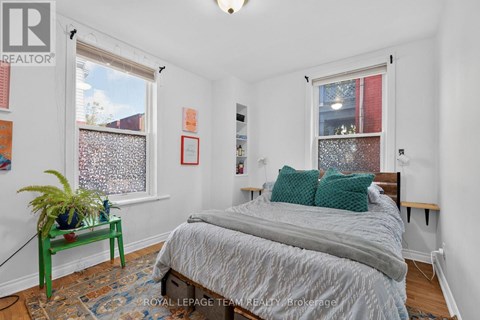 A bedroom with a bed, nightstand, and window.
