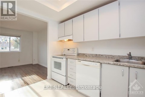 A kitchen with white cabinets and appliances is for sale.