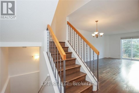 A staircase with a wooden handrail and white balusters leads to a bright room.