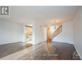A spacious room with wooden floors and a staircase leading to another room.