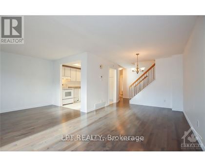A spacious room with wooden floors and a staircase leading to another room.