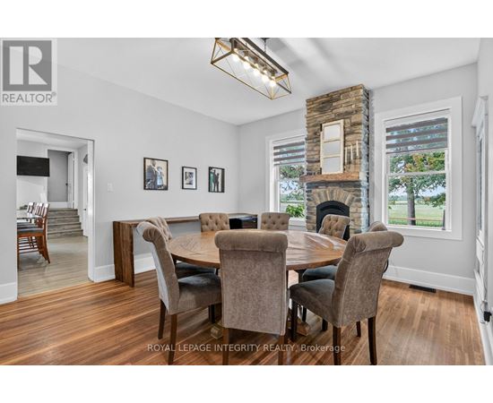 A dining room with a stone fireplace and a table set for six.