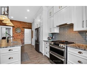 A kitchen with white cabinets and a brick wall.