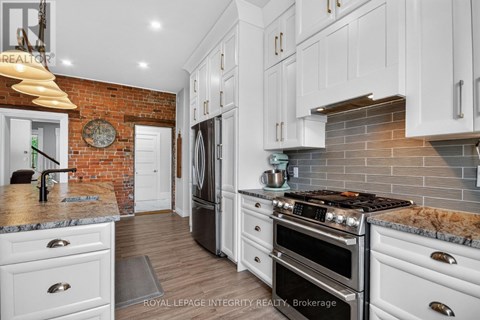 A kitchen with white cabinets and a brick wall.