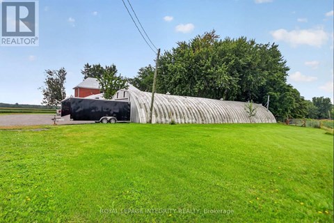 A large building with a grey roof is surrounded by a grassy field.
