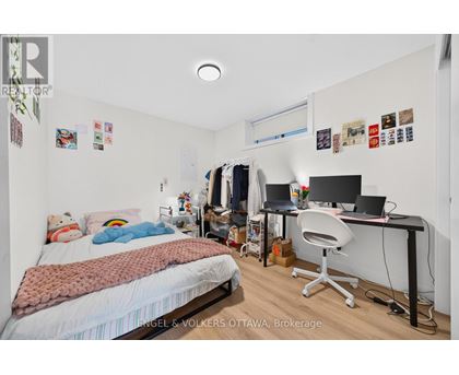 A bedroom with a bed, desk, and clothing rack.
