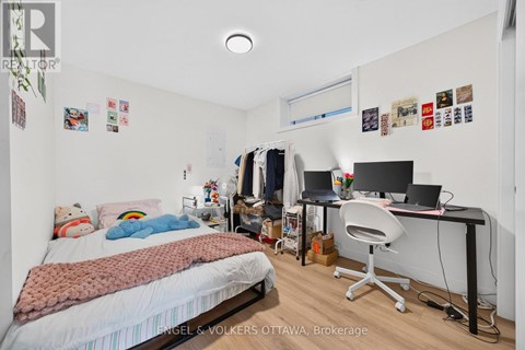 A bedroom with a bed, desk, and clothing rack.