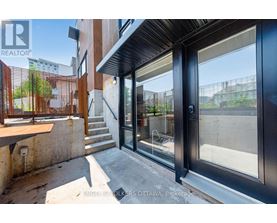 A modern house entrance with a glass door and a wooden railing.
