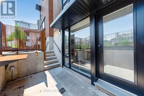 A modern house entrance with a glass door and a wooden railing.