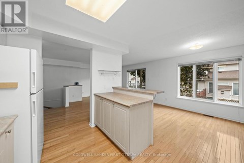 A spacious kitchen with wooden floors and white walls.