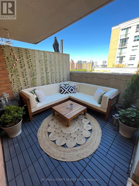 A patio with a couch, table, and potted plants.
