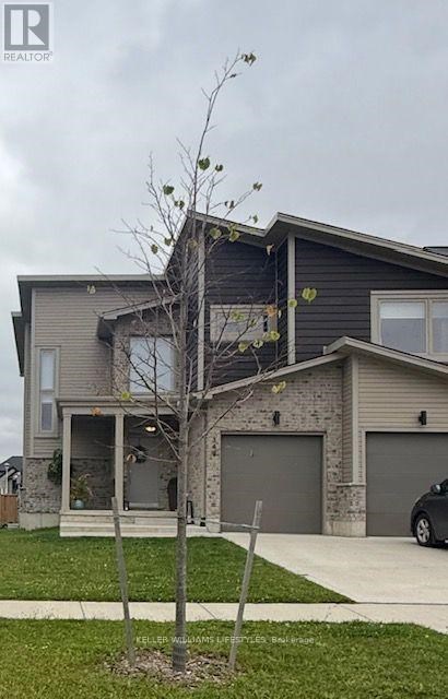A house with a grey garage door and a tree in front.