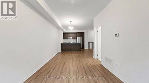 A long hallway with a white wall and a brown floor.